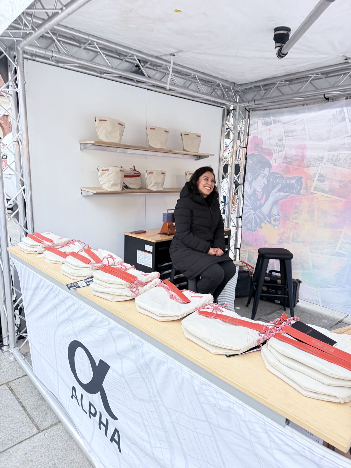 Live event with a person demonstrating screen printing at a professional booth with hanging printed apparel